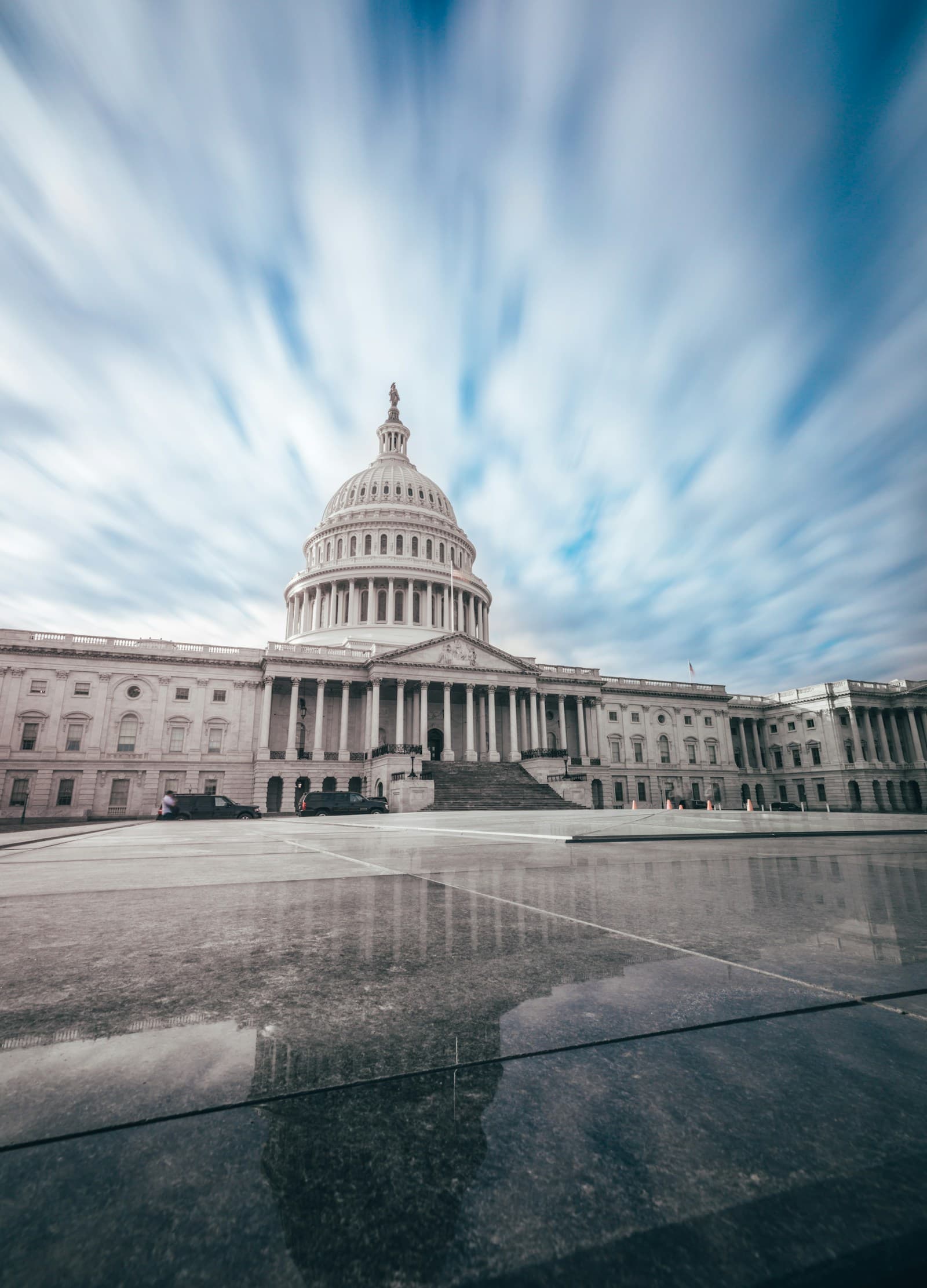 The United States Capitol building photographed from the plaza beneath a streaked, overcast sky