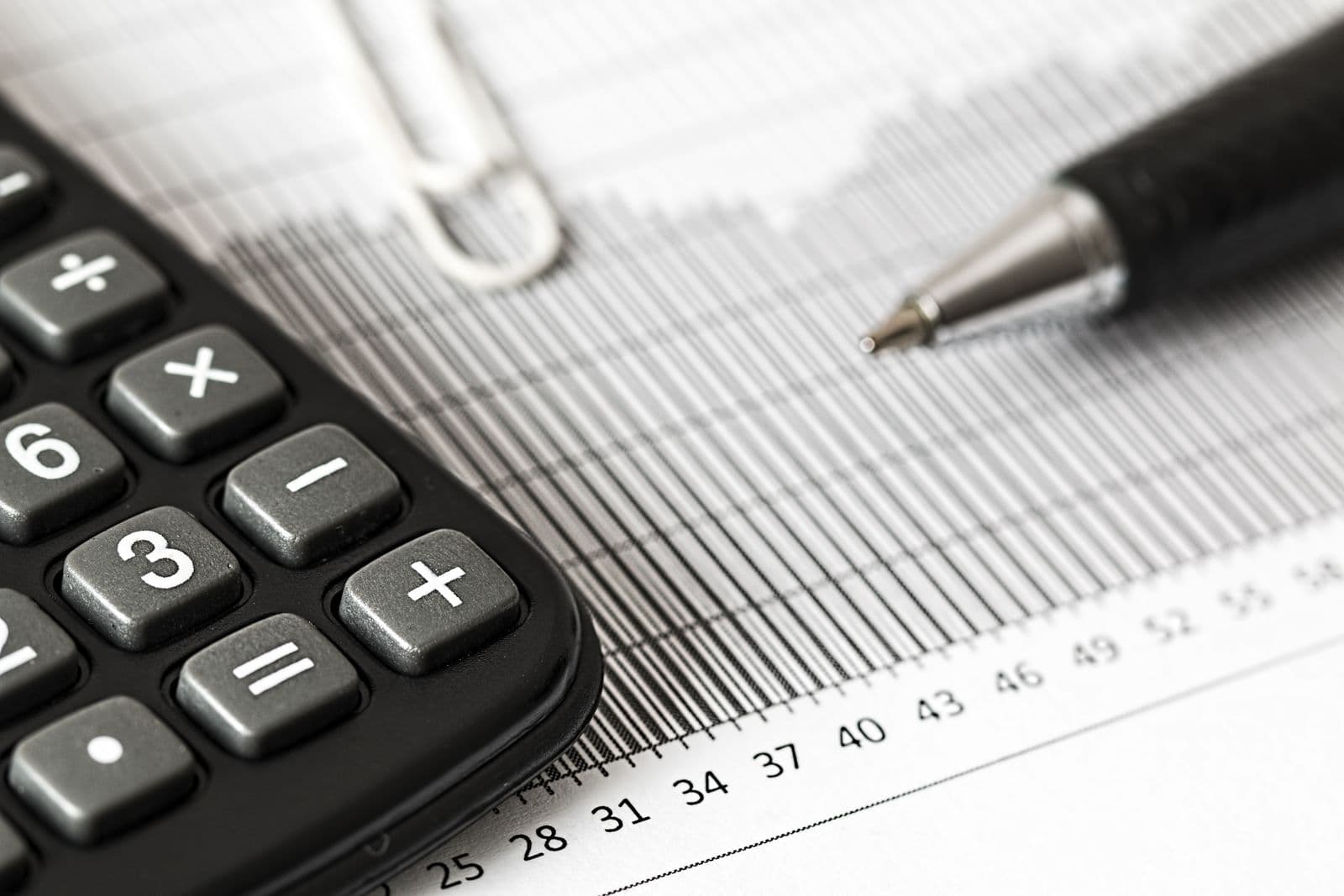 Calculator and pen resting on a printed financial bar chart