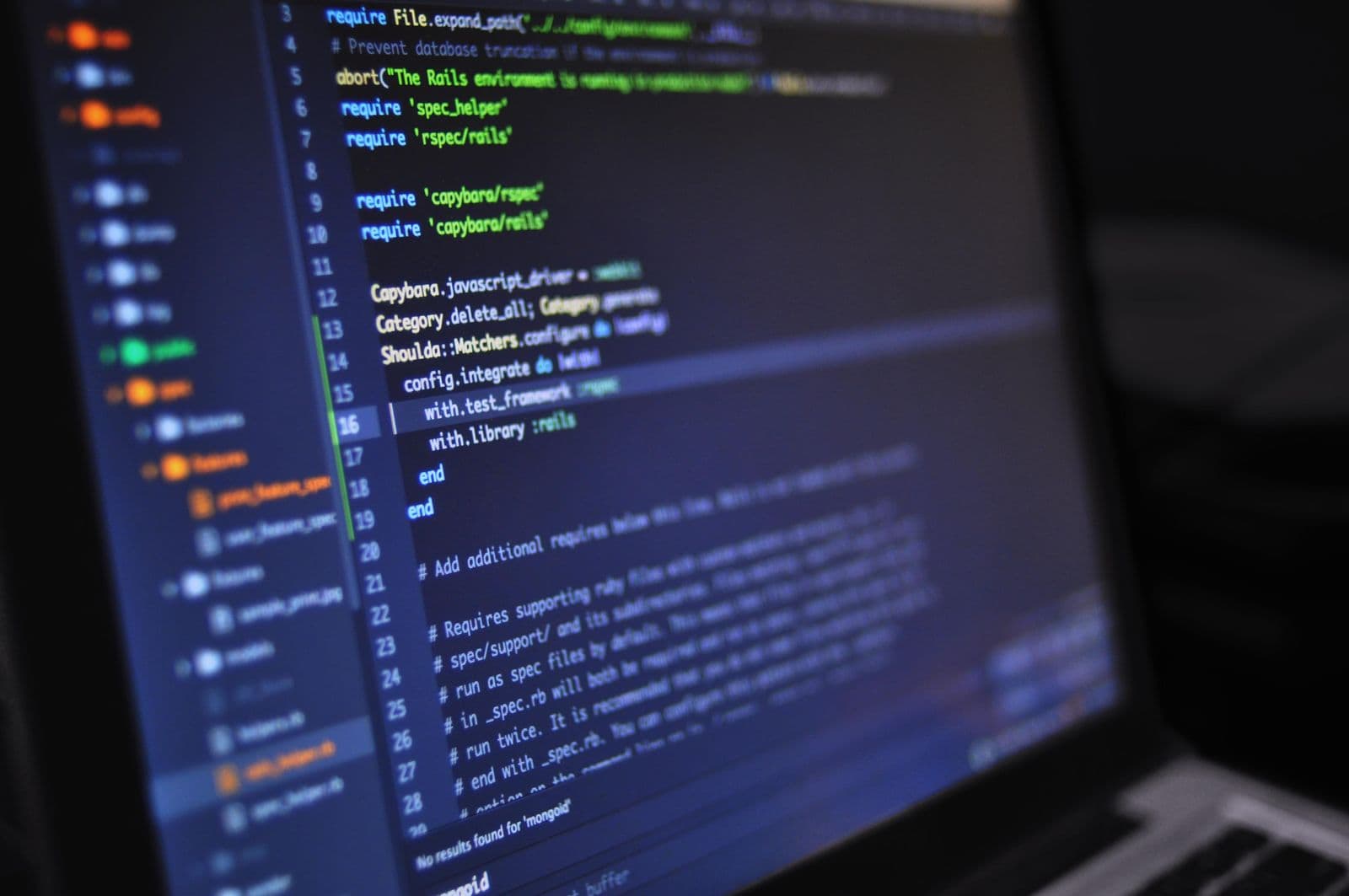 A laptop screen at an angle showing a code editor with syntax-highlighted configuration on a dark background