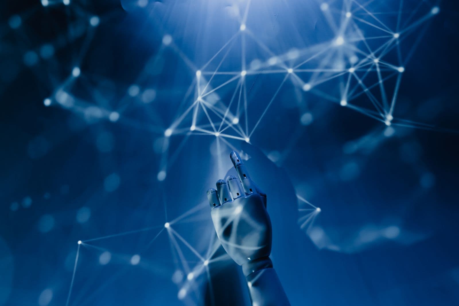 A white robotic hand reaching upward into a glowing blue web of connected points and lines