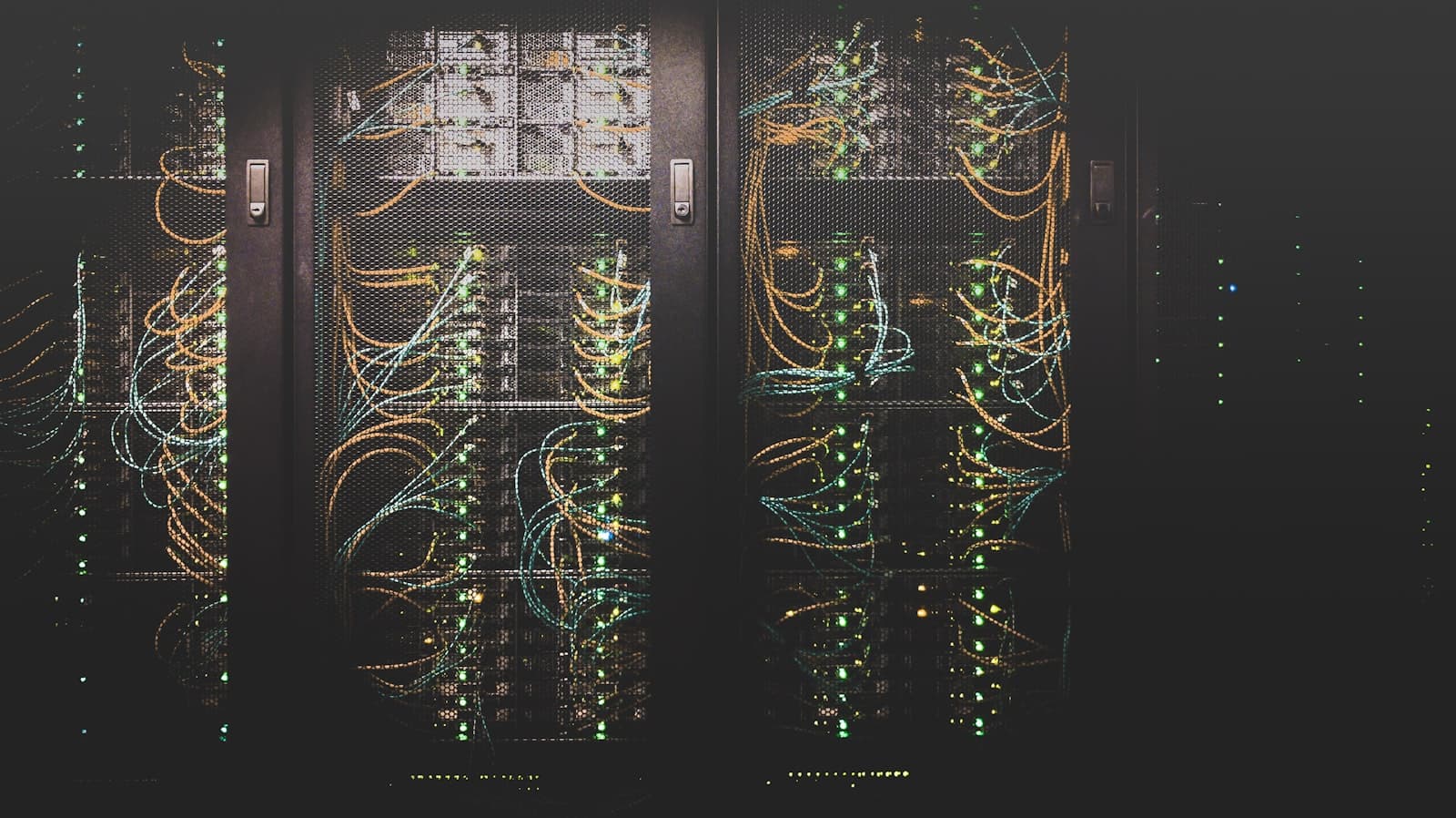 Server racks with bundled network cables and glowing green status lights in a dark data center